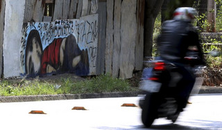 A motorcycle rides past a graffiti depicting the drowned Syrian toddler Aylan Kurdi in Sorocaba, Brazil, September 5, 2015. Brazil's President Dilma Rousseff criticized European nations on Friday for creating "barriers" to the entry of migrants, saying the Syrian child found on a beach in Turkey had died because he was "not welcome." Three-year-old Aylan Kurdi died along with his mother and 5-year-old brother as they attempted to cross the Mediterranean to Greece. Photographs of Kurdi, washed up dead on the shores of Turkey, shocked the world and led to a wave of criticism against the way Europe is dealing with the thousands of refugees fleeing conflict in the Middle East. The graffiti reads: "Peace, peace, peace, abandoned". Picture taken September 5, 2015.  REUTERS/Paulo Whitaker