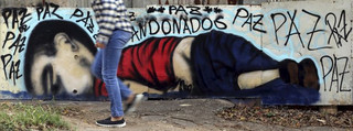 A person walks past a graffiti depicting the drowned Syrian toddler Aylan Kurdi in Sorocaba, Brazil, September 5, 2015. Brazil's President Dilma Rousseff criticized European nations on Friday for creating "barriers" to the entry of migrants, saying the Syrian child found on a beach in Turkey had died because he was "not welcome." Three-year-old Aylan Kurdi died along with his mother and 5-year-old brother as they attempted to cross the Mediterranean to Greece. Photographs of Kurdi, washed up dead on the shores of Turkey, shocked the world and led to a wave of criticism against the way Europe is dealing with the thousands of refugees fleeing conflict in the Middle East. The graffiti reads: "Peace, peace, peace, abandoned". Picture taken September 5, 2015. REUTERS/Paulo Whitaker