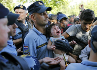 A Croatian policeman holds a crying baby as he stands among migrants waiting to board a bus in Tovarnik, Croatia, September 17, 2015. Croatia said on Thursday it could not take in any more migrants, amid chaotic scenes of riot police trying to control thousands who have streamed into the European Union country from Serbia.  REUTERS/Antonio Bronic TPX IMAGES OF THE DAY
