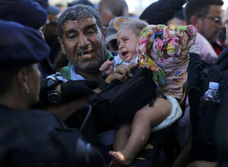 A migrant holds a baby as he waits to board a bus in Tovarnik, Croatia, September 17, 2015. The European Union's migration chief Dimitris Avromopoulos rebuked Hungary on Thursday for its tough handling of a flood of refugees as asylum seekers thwarted by a new Hungarian border fence and repelled by riot police poured into Croatia, spreading the strain. REUTERS/Antonio Bronic