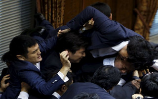 Opposition Democratic Party of Japan lawmaker Konishi climbs over other lawmakers who are guarding Konoike, chairman of the upper house special committee on security, at the parliament in Tokyo