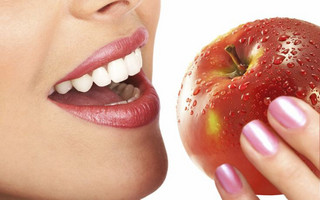 Beautiful young woman eating red apple. Isolated over white