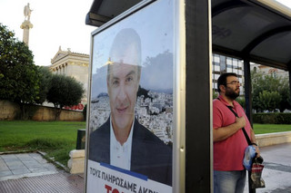 A man stands at a bus stop decorated with a pre-election poster with an image of leader of the centre-left To Potami party Stavros Theodorakis in Athens, Greece, September 17, 2015. Greece's leftist Syriza party has a 0.6 percentage point lead over the conservative New Democracy party, a Kapa Research poll for To Vima newspaper showed on Thursday. REUTERS/Michalis Karagiannis