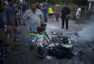 A migrant pushes a cart with children inside as they pass burning remains of the clashes earlier today at the border with Hungary near the village of Horgos, Serbia, September 16, 2015.Twenty Hungarian policemen and two children were injured on the Hungarian border with Serbia in clashes that erupted after a group of migrants tried to break through the frontier, the prime minister's security adviser said. REUTERS/Stoyan Nenov