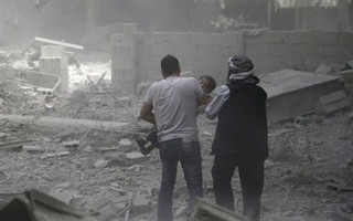 Men help an injured boy who survived what activists said were airstrikes by forces loyal to Syria's President Bashar al-Assad, in the Douma neighborhood of Damascus