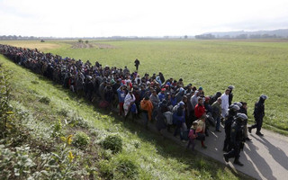 Policemen lead a group of migrants near Dobova, Slovenia October 20, 2015. Slovenia's parliament is expected to approve changes to its laws later on Tuesday to enable the army to help police guard the border, as thousands of migrants flooded into the country from Croatia after Hungary sealed off its border. REUTERS/Srdjan Zivulovic