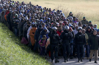 Policemen lead a group of migrants near Dobova, Slovenia October 20, 2015. Migrants continue to stream north through the Balkans from Greece but Hungary sealed its border with Croatia on Friday and Slovenia imposed daily limits on migrants entering from Croatia, leaving thousands stuck on cold, rain-sodden frontiers. REUTERS/Srdjan Zivulovic