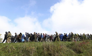 Slovenian policemen and soldiers lead a group of migrants near Dobova, Slovenia October 20, 2015. Migrants continue to stream north through the Balkans from Greece but Hungary sealed its border with Croatia on Friday and Slovenia imposed daily limits on migrants entering from Croatia, leaving thousands stuck on cold, rain-sodden frontiers. REUTERS/Srdjan Zivulovic