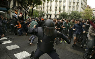 Spanish riot police swings a club against would-be voters near a school assigned to be a polling station by the Catalan government in Barcelona, Spain, Sunday, Oct. 1, 2017. Spanish riot police have forcefully removed a few hundred would-be voters from several polling stations in Barcelona. (AP Photo/Manu Fernandez)