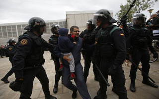 Civil guards force a man with a child to leave the entrance of a sports center, assigned to be a referendum polling station by the Catalan government in Sant Julia de Ramis, near Girona, Spain, Sunday, Oct. 1, 2017. Scuffles have erupted as voters protested as dozens of anti-rioting police broke into a polling station where the regional leader was expected to show up for voting on Sunday. (AP Photo/Francisco Seco)