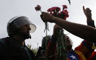 People try to offer flowers to a civil guard at the entrance of a sports center, assigned to be a referendum polling station by the Catalan government in Sant Julia de Ramis, near Girona, Spain, Sunday, Oct. 1, 2017. Scuffles have erupted as voters protested while dozens of anti-rioting police broke into a polling station where the regional leader was expected to show up for voting on Sunday. (AP Photo/Francisco Seco)