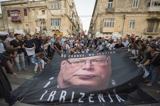 A banner with the photo of the Malta police commissioner Lawrence Cutajar is laid on the floor outside the Malta Police Headquarters during a spontaneous protest which followed a rally to honor anti-corruption reporter Daphne Caruana Galizia, killed by a car bomb on Oct. 16, in the capital city of Malta, Valletta, Sunday, Oct. 22, 2017. (AP Photo/Rene Rossignaud)