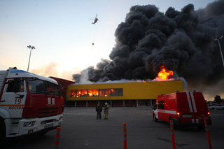 An helicopter dumps water on a fire at a shopping mall, just outside Moscow, Russia, Sunday, Oct. 8, 2017. A number of cars have exploded at the underground parking garage of the Sindika trade center engulfed in fire at Moscow's outer circular road, a source in the emergencies services told TASS on Sunday. ( Sergey Vedyashkin/Moscow News Agency photo via AP)