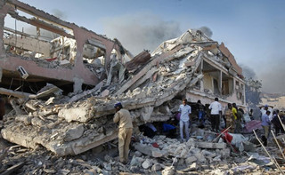 Somalis gather and search for survivors by destroyed buildings at the scene of a blast in the capital Mogadishu, Somalia Saturday, Oct. 14, 2017. A huge explosion from a truck bomb has killed at least 20 people in Somalia's capital, police said Saturday, as shaken residents called it the most powerful blast they'd heard in years. (AP Photo/Farah Abdi Warsameh)