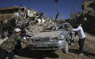 People and rescuers move a destroyed car on the earthquake site in Sarpol-e-Zahab in western Iran, Tuesday, Nov. 14, 2017. Rescuers are digging through the debris of buildings felled by the Sunday earthquake in the border region of Iran and Iraq. (AP Photo/Vahid Salemi)