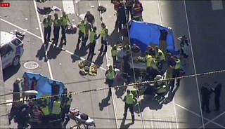 In this photo made video from the Australian Broadcasting Corp., emergency medical workers offer aid to victims struck by a vehicle, Thursday, Dec. 21, 20217, in Melbourne, Australia. Local media say over a dozen people have been injured after a car drove into pedestrians on a sidewalk in central Melbourne. (Australian Broadcast Corp. via AP)