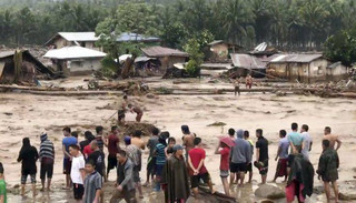 In this photo made from video by Aclimah Disumala, Friday, Dec. 22, 2017, villagers carry cross raging flood waters in Lanao del Norte, Zamboanga Pennisula, southern Philippines. A tropical storm has unleashed flash floods and set off landslides in the southern Philippines leaving dozens of people dead. (Aclimah Disumala via the AP)