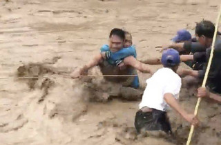 In this photo made from video by Aclimah Disumala, Friday, Dec. 22, 2017, villagers carry an elderly woman across raging flood waters in Lanao del Norte, Zamboanga Pennisula, southern Philippines. A tropical storm has unleashed flash floods and set off landslides in the southern Philippines leaving dozens of people dead. (Aclimah Disumala via the AP)