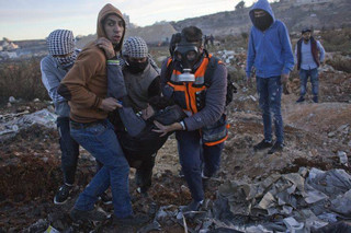 Palestinian protesters evacuate an injured fellow toward an ambulance during clashes with Israeli troops following protests against U.S. President Donald Trump's decision to recognize Jerusalem as the capital of Israel, in the West Bank city of Ramallah, Saturday, Dec. 9, 2017. (AP Photo/Nasser Nasser)