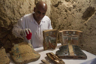 An Egyptian excavation worker restores funeral furniture found in a newly discovered tombon Luxor's West Bank known as "KAMPP 161" during an announcement for the Egyptian Ministry of antiquities about new discoveries in Luxor, Egypt, Saturday, Dec. 9, 2017. Egypt's Antiquities Ministry says archaeologists have discovered two ancient tombs in the southern city of Luxor. The ministry said Saturday that one tomb has five entrances leading to a rectangular hall, and contains painted wooden funerary masks, clay vessels and a mummy wrapped in linen. (AP Photo/Hamada Elrasam)