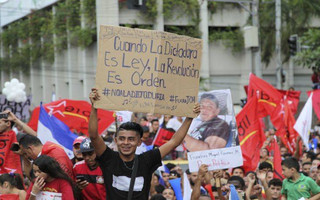 An opposition supporter carries a sign with a message that reads in Spanish: "When dictatorship is the law, revolution is an order," during an opposition protest in support of Salvador Nasralla, in San Pedro Sula, Honduras, Saturday, Jan. 6, 2018. Following a disputed election marred by irregularities, incumbent Juan Orlando Hernandez was declared the victor and will be inaugurated on Jan. 27. At a march and rally that drew thousands, Nasralla said he would not stop calling for protests and civil disobedience until Hernandez agrees to step down. (AP Photo/Fernando Antonio)