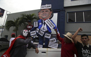Opposition supporters rally alongside a cardboard figure of President Juan Orlando Hernandez, labelled with Spanish phrases including "dictator" and "mega electoral fraud," during a rally where opposition leader Salvador Nasralla reaffirmed his claim on the presidency, in San Pedro Sula, Honduras, Saturday, Jan. 6, 2018. Following a disputed election marred by irregularities, incumbent Hernandez was declared the victor and will be inaugurated on Jan. 27. At a march and rally that drew thousands, Nasralla said he would not stop calling for protests and civil disobedience until Hernandez agrees to step down. (AP Photo/Fernando Antonio)