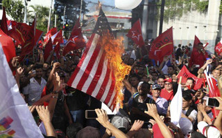 Opposition supporters burn a flag of the United States, which recognized disputed election results handing victory in November's presidential election to incumbent Juan Orlando Hernandez, during a march and rally led by opposition leader Salvador Nasralla in San Pedro Sula, Honduras, Saturday, Jan. 6, 2018. Following an election marred by irregularities, Hernandez was declared the victor and will be inaugurated on Jan. 27. Nasralla reaffirmed his claim on the presidency and said he would not stop calling for protests and civil disobedience until Hernandez agrees to step down. (AP Photo/Fernando Antonio)