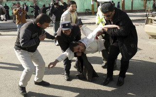 A wounded man is assisted at the site of a deadly suicide attack in the center of Kabul, Afghanistan, Saturday, Jan. 27, 2018. Afghan Public Health Ministry says dozens have been killed and over 100 wounded in suicide car bomb attack in capital Kabul. (AP Photo/Massoud Hossaini)