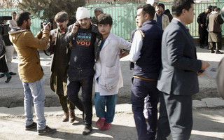 A wounded man is assisted at the site of an explosion in downtown Kabul, Afghanistan, Saturday, Jan. 27, 2018. The Interior Ministry says a suicide car bomb attack in Kabul has left dozens wounded. (AP Photo/Massoud Hossaini)