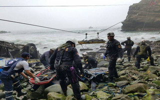 In this handout photo provided by the Ministry of Peru, police help in the continued recovery of bodies a day after a bus fell off a cliff, in Pasamayo, Peru, Wednesday, Jan. 3, 2018. Peruvian officials say at least 48 people are dead after the bus tumbled down a cliff along a narrow stretch of highway known as the "Devil's Curve." The bus was carrying passengers to Peru's capital when it was struck by a tractor trailer shortly before noon Tuesday and plunged down the slope. (Ministry of Peru via AP)