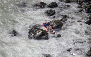 In this photo provided by the government news agency Andina, an injured man is transported over water from a bus that fell off a cliff after it was hit by a tractor-trailer rig, in Pasamayo, Peru, Tuesday, Jan. 2, 2018. A Peruvian police official says at least 25 people died, and that there were more than 50 people on the bus. (Vidal Tarky, Andina News Agency via AP)