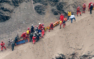 In this photo provided by the government news agency Andina, rescue workers surround an injured man on a stretcher who was lifted up from the site of a bus crash at the bottom of a cliff, after the bus was hit by a tractor-trailer rig in Pasamayo, Peru, Tuesday, Jan. 2, 2018. A Peruvian police official says at least 25 people died, and that there were more than 50 people on the bus. (Vidal Tarky, Andina News Agency via AP)