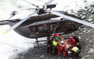 In this photo provided by the government news agency Andina, rescue workers load an injured man on a stretcher after he was retrieved from a bus that fell off a cliff after it was hit by a tractor-trailer rig, in Pasamayo, Peru, Tuesday, Jan. 2, 2018. A Peruvian police official says at least 25 people died, and that there were more than 50 people on the bus. (Vidal Tarky/Andina News Agency via AP)