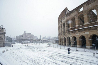 People walk along the ancient Colosseum blanketed by the snow in Rome, Monday, Feb. 26, 2018. (AP Photo/Alessandra Tarantino)