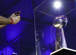 A man takes a photograph of the Vince Lombardi Trophy at the NFL Experience football fan attraction Friday, Feb. 2, 2018, in Minneapolis. The New England Patriots and the Philadelphia Eagles are scheduled to play in Super Bowl 52 Sunday, Feb. 4. (AP Photo/Mark Humphrey)