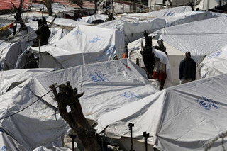 In this photo taken on Thursday, March 16, 2017 an African migrant stands between tents at the Moria refugee detention center on the northeastern Greek island of Lesbos. The waters off northern Lesbos once resounded to the shrieks of the drowning, the whine of outboard motors as refugees struggled to reach Europe alive, and the thudding of rescue helicopter engines. A million people crossed the straits between Turkey and Greece’s eastern Aegean islands in the year before March 20, 2016, and hundreds drowned. About half of those who made it landed on this island.  (AP Photo/Thanassis Stavrakis)