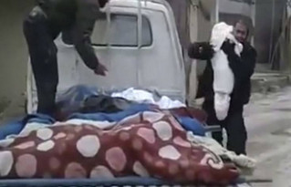 This frame grab from video provided on Wednesday Feb. 21, 2018 by the Syrian anti-government activist group Ghouta Media Center, which has been authenticated based on its contents and other AP reporting, shows a Syrian man, right, hugging and saying his last goodbye to his dead child who was killed during airstrikes and shelling by Syrian government forces, as he walks to bury him in a mass grave, in Ghouta, suburb of Damascus, Syria. It is a grief shared by all too many parents trapped with their children under a brutal, government siege of the Eastern Ghouta region outside the Syrian capital of Damascus. The government, backed by Russia, is determined to bring the once rebellious region back under its authority. (Ghouta Media Center via AP)