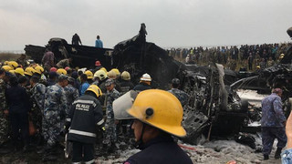 Nepalese rescuers stand near a passenger plane from Bangladesh that crashed at the airport in Kathmandu, Nepal, Monday, March 12, 2018. (AP Photo/Niranjan Shreshta)