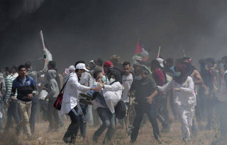 Palestinian medics evacuate a wounded colleague during clashes with Israeli troops along Gaza's border with Israel, east of Khan Younis, Friday, April 6, 2018. Palestinians torched piles of tires near Gaza's border with Israel on Friday, sending huge plumes of black smoke into the air and drawing Israeli fire that killed one man in the second large protest in the volatile area in a week. (AP Photo/Adel Hana)