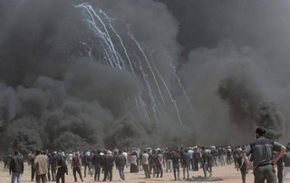 Palestinian protesters gather in front of burned tires while Israeli soldiers fire teargas during clashes with Israeli troops along Gaza's border with Israel, Friday, April 6, 2018. Palestinians torched piles of tires near Gaza's border with Israel on Friday, sending huge plumes of black smoke into the air and drawing Israeli fire that killed one man in the second large protest in the volatile area in a week. (AP Photo/Adel Hana)