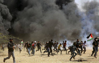Palestinian protesters run to cover from teargas fired by Israeli soldiers during clashes with Israeli troops along Gaza's border with Israel, east of Khan Younis, Gaza Strip, Friday, April 6, 2018. Palestinians torched piles of tires near Gaza's border with Israel on Friday, sending huge plumes of black smoke into the air and drawing Israeli fire that killed one man in the second large protest in the volatile area in a week. (AP Photo/Adel Hana)