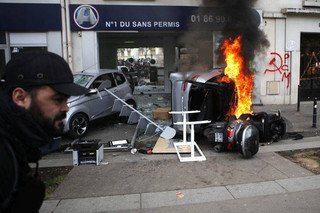 A man runs past a burning car and scooter set on fire by activists activists during the traditional May Day rally in the center of Paris, France, Tuesday, May 1, 2018. Each year, people around the world take to the streets to mark International Workers' Day, or May Day. (AP Photo/Francois Mori)