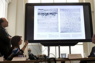 A video shows the text underneath two taped off pages from Anne Frank's diary during a press conference at The Anne Frank Foundation's office in Amsterdam, Netherlands, Tuesday, May 15, 2018. Left standing is the foundation's director Ronald Leopold. Researchers have used digital photo editing techniques to uncover the text on two pages from Anne Frank's world famous diary that the teenage Jewish diarist had covered with brown masking paper, revealing risque jokes and an explanation of sex and prostitution. (AP Photo/Peter Dejong)