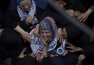 Relatives of Palestinian volunteer paramedic Razan Najjar, 21, mourn at the family house during her funeral in town of Khan Younis, southern Gaza Strip, Saturday, June 2, 2018. Najjar was killed by Israeli fire Friday during mass protests in the Gaza Strip, the Palestinian Health Ministry said. (AP Photo/Khalil Hamra)