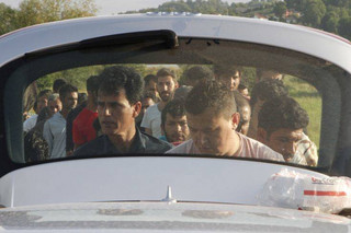 In this photo taken on Saturday, June 9, 2018, migrants accommodated in a makeshift tent camps in Velika Kladusa, 400 kms north west of Bosnian capital of Sarajevo, wait in line to receive food, cooked and delivered by local residents. The restaurant owner Asim Latic from northwestern Bosnia in February closed down his pizzeria for regular guests and is now serving only meals for migrants passing through the Balkan nation while trying to reach Western Europe. (AP Photo/Amel Emric)