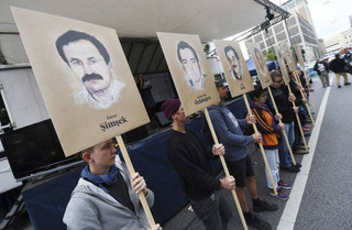 Demonstrators hold signs with people killed by the NSU outside the court in Munich, southern Germany, prior to the verdict Wednesday, July 11, 2018. (Tobias Hase/dpa via AP)