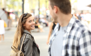 Γυναίκα χαμογελάει σε έναν άντρα που περνά δίπλα της στον δρόμο