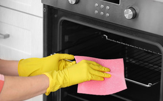 Γυναίκα καθαρίζει τη σχάρα του φούρνου