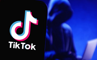 Οθόνη που γράφγει TikTok και μία μορφή με κουκούλα