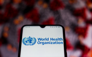 Logo του Παγκόσμιου Οργανισμού Υγείας (ΠΟΥ) με φόντο τον κορονοϊό